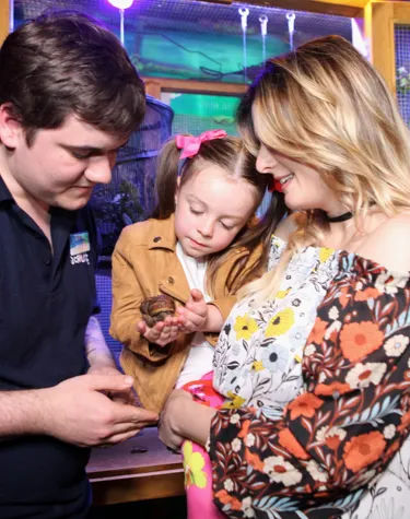 Guests with a rainforest ranger holding a snail at SEA LIFE