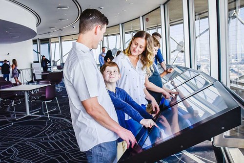 Visitors using interactive displays at the observation deck inside the Reunion Tower