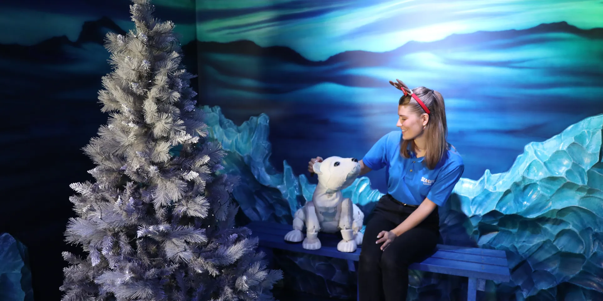 SEA LIFE London staff member with Al the Polar Bear Puppet besides a Christmas tree 