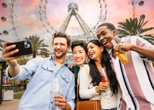 Four friends posing infront of Orlando Eye with drinks