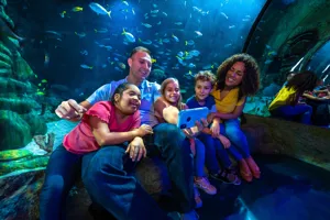A family of five gathering for a selfie in front of exhibit at SEA LIFE Orlando