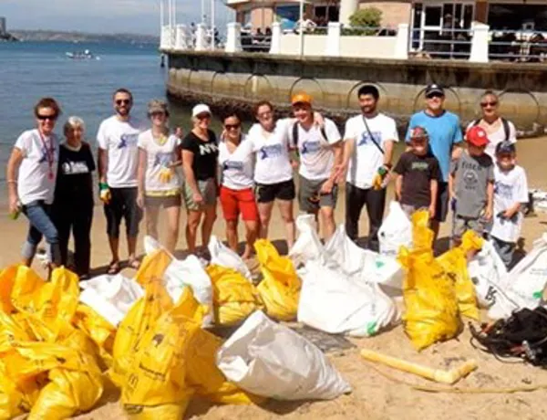 Group of people cleaning the beach with recycled bags