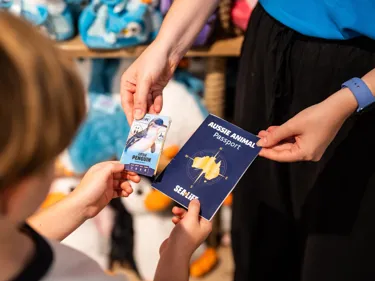 Child receiving a Little Penguin activity card alongside an Aussie Animal Passport at SEA LIFE Sydney Aquarium