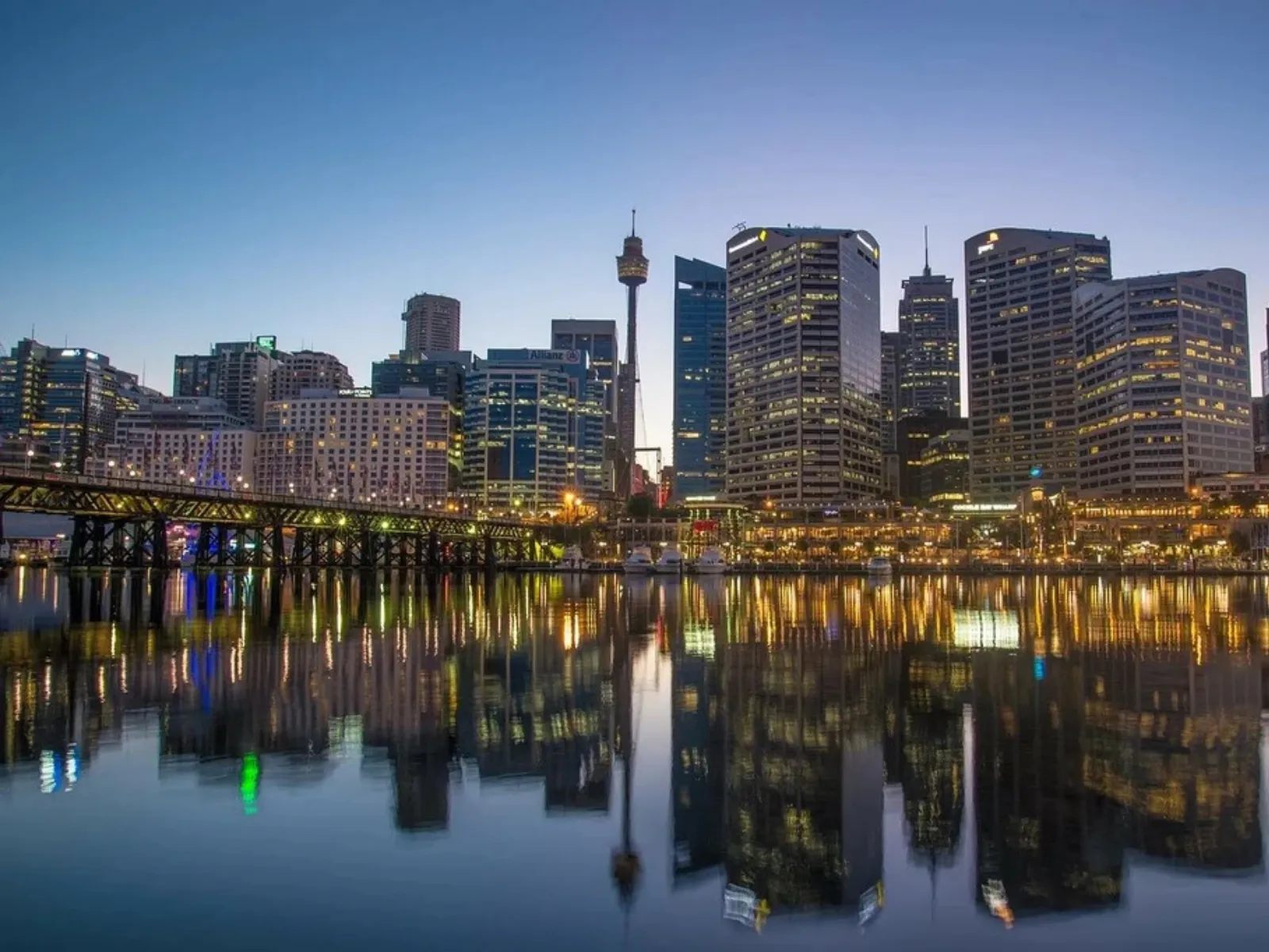 Sydney skyline at Darling Harbour reflected on the water at dusk near family attractions, SEA LIFE Sydney Aquarium, WILD LIFE Sydney Zoo, Madame Tussauds Sydney and Sydney Tower Eye