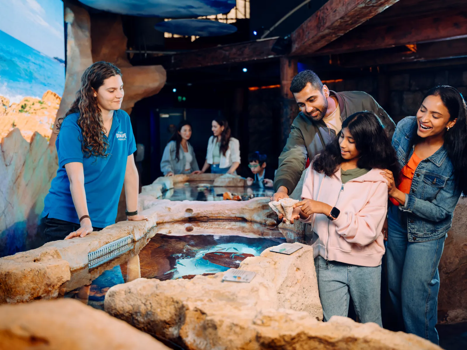 Family smiling and enjoying the interactive Rockpool Ranger exhibit at SEA LIFE Sydney Aquarium